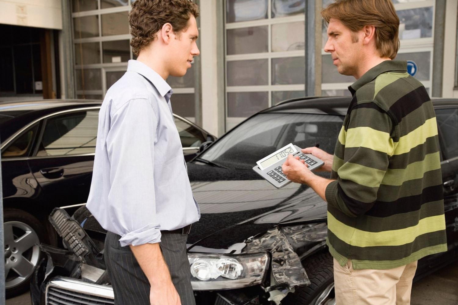 Two drivers exchanging contact and insurance details after a car accident